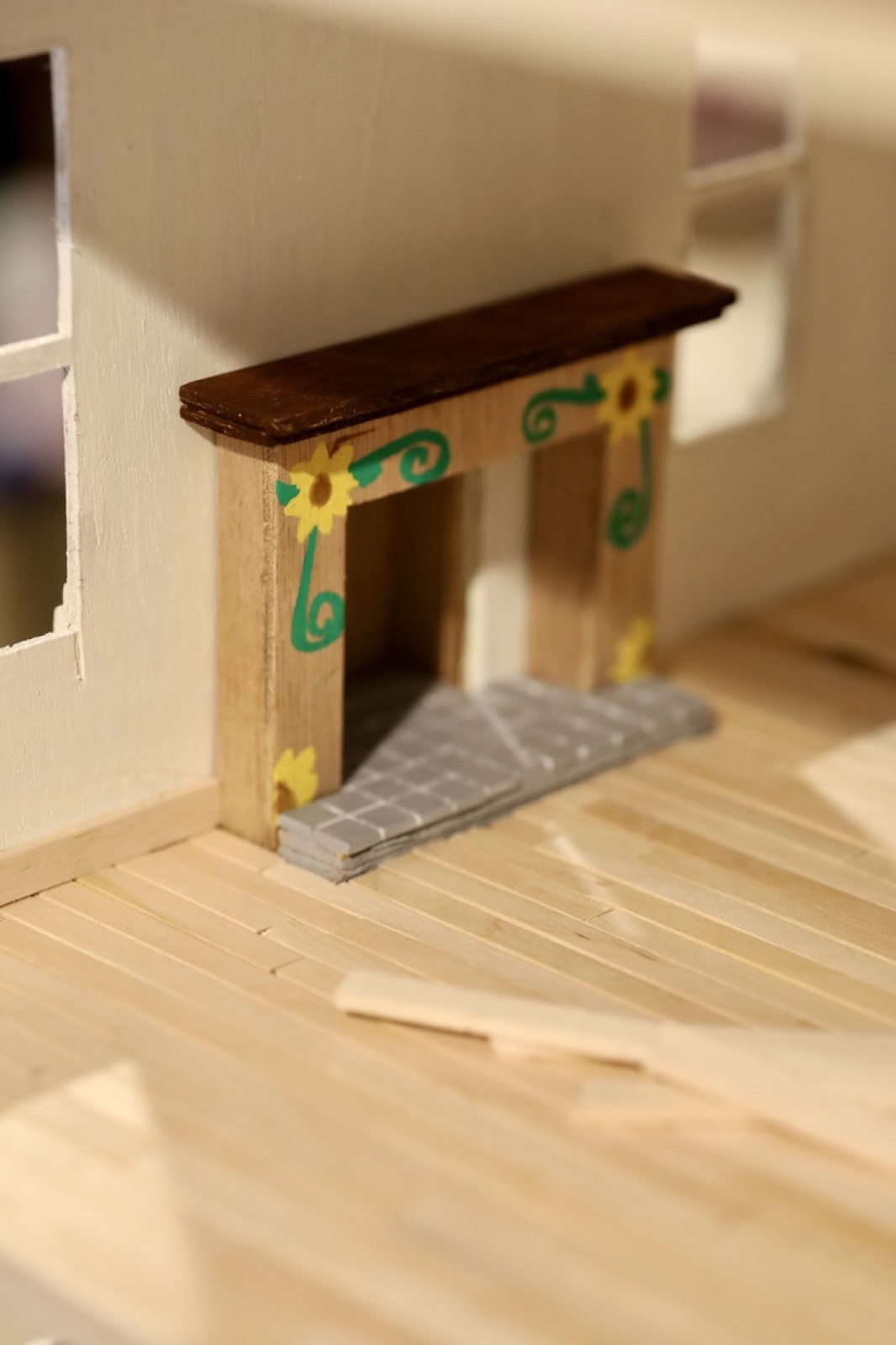 Handmade miniature fireplace with sunflower details inside the unfinished doll house