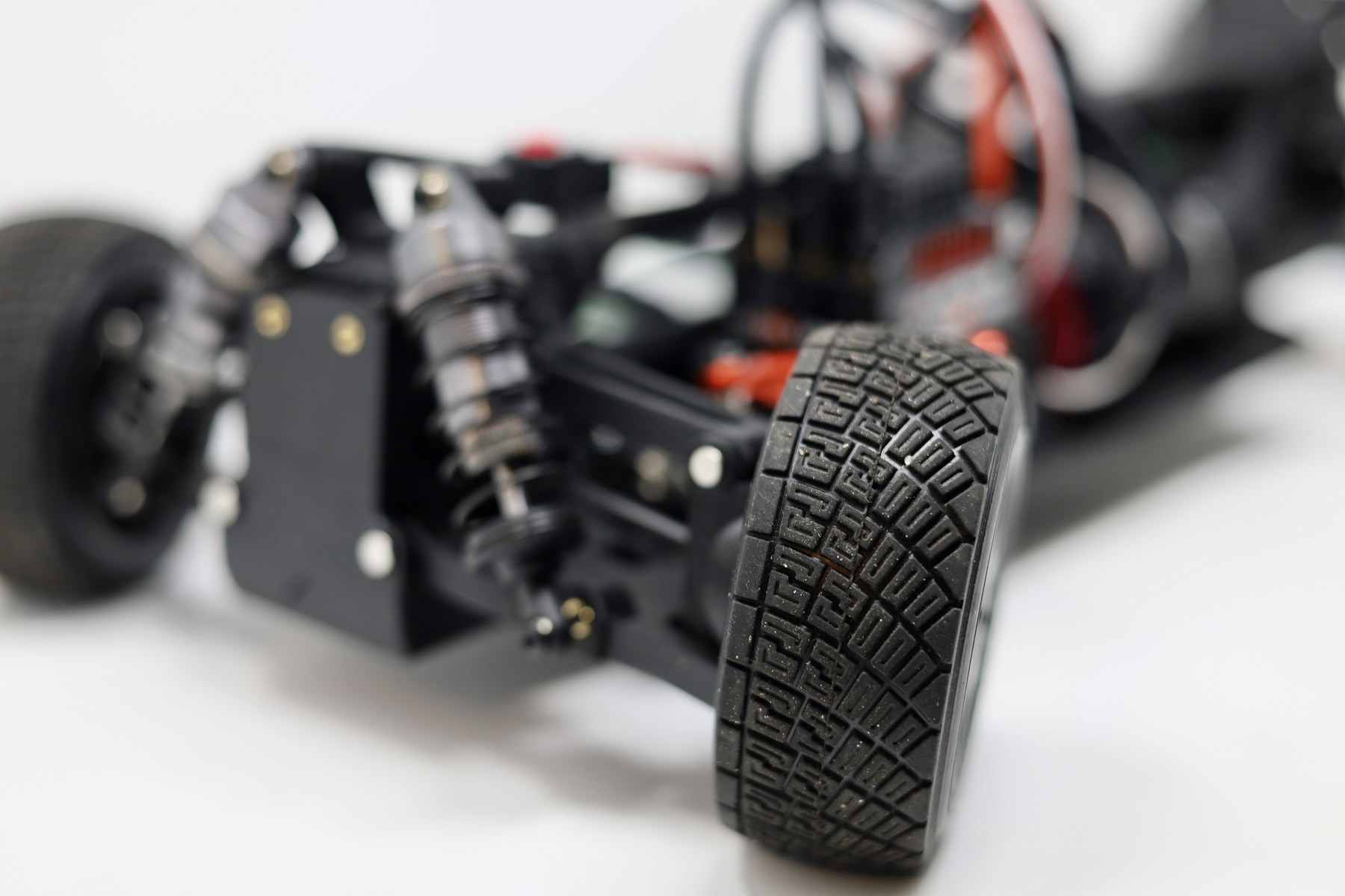 Close-up of a 3D printed RC car chassis with the front tire in focus